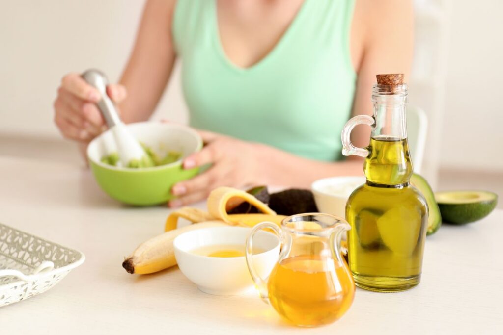 woman mixing avocado with bottle of olive oil